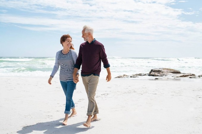 Two adults walking on beach holding hands